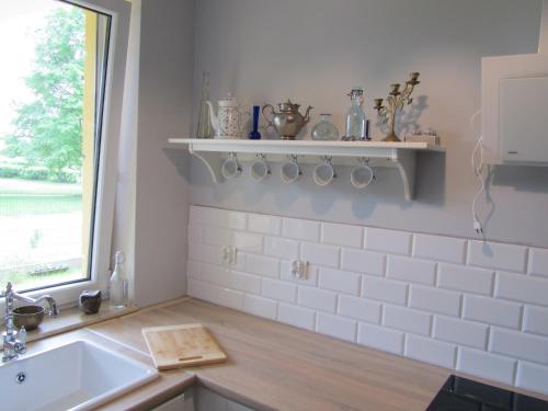 biała kuchnia ze zlewem i oknem w obiekcie Apartament Marycha Sejny w Sejnach