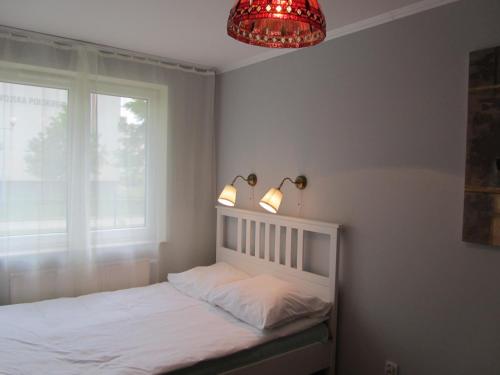 a bedroom with a bed and a window and a chandelier at Apartament Marycha Sejny in Sejny