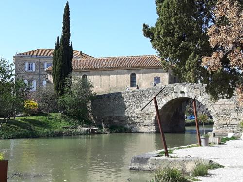kamienny most nad rzeką przed budynkiem w obiekcie La Vigne Des Heures Claires w mieście Saint-Nazaire-dʼAude