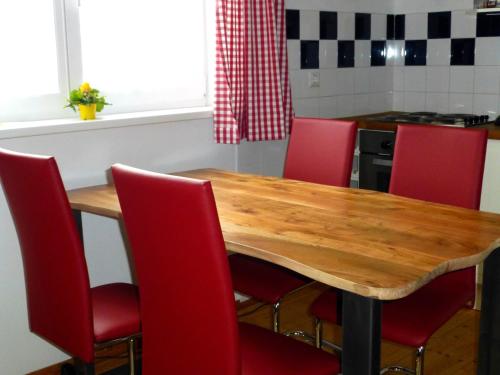 a kitchen with a wooden table and red chairs at Appartment Almenliesl in Gosau