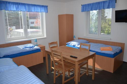 a room with two beds and a table and chairs at Penzion 411 in Solnice