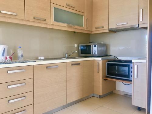 a kitchen with wooden cabinets and a microwave and a sink at Rossi apartment in Hersonissos