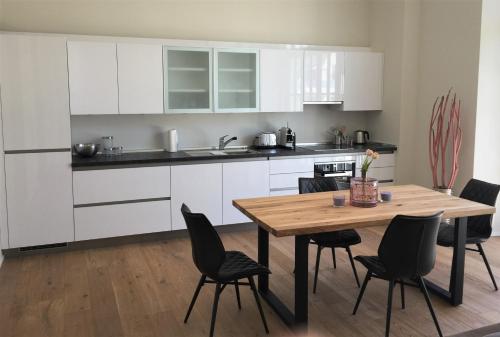 a kitchen with white cabinets and a wooden table and chairs at Anker Guest House in Bielefeld