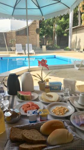 a table topped with plates of food next to a pool at Hotel - Apart-hotel Chalé Executivo in Mossoró