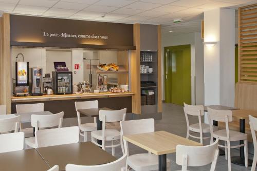 a restaurant with white chairs and tables and a counter at B&B HOTEL Nantes Savenay in Savenay