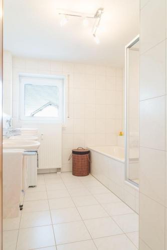 a white bathroom with a tub and a sink at Ferienwohnung Schwedi in Langenargen