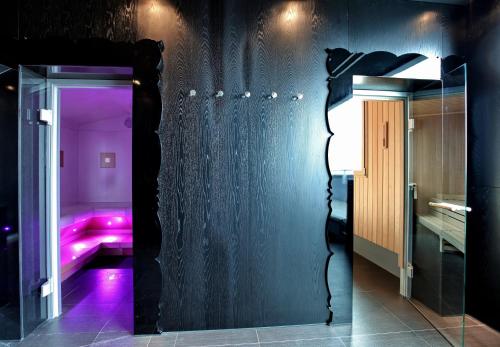 a room with a mirror and a room with pink lights at Falkensteiner Hotel Belgrade Superior in Belgrade