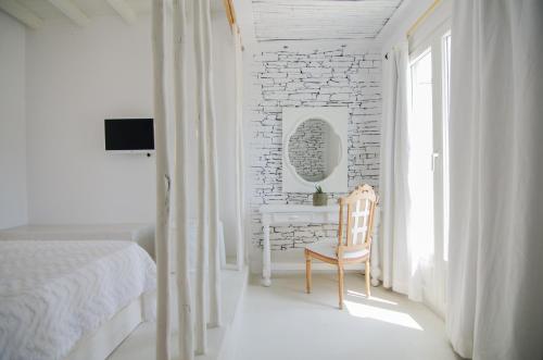 a bedroom with a bed and a chair and a desk at Levantes Ios Boutique Hotel in Mylopotas