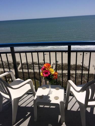 a table with chairs and a vase of flowers on a balcony at Boardwalk Beach Resort in Myrtle Beach