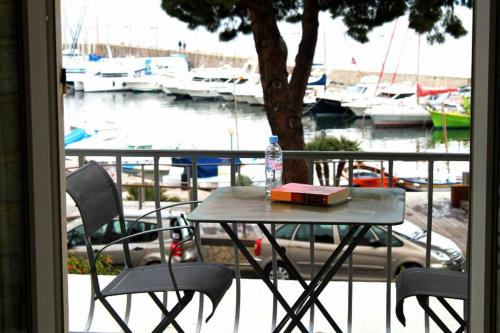 - une table avec un livre sur un balcon avec des bateaux dans l'établissement Hôtel Le Richiardi, à Carqueiranne
