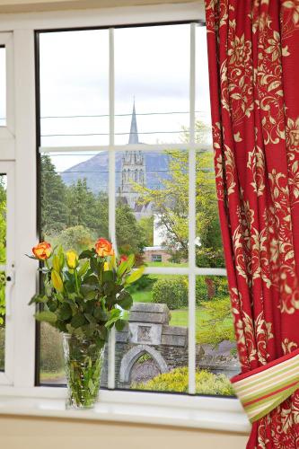 a window with a vase with flowers on a window sill at Ashville House in Killarney