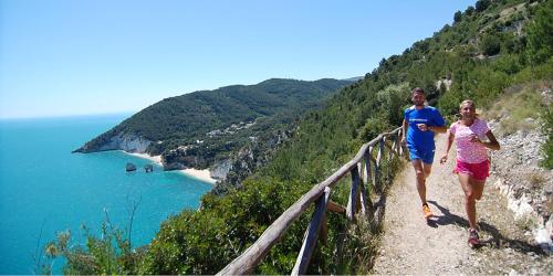 two people walking on a trail near the ocean at Casa MARESOLE in Mattinata