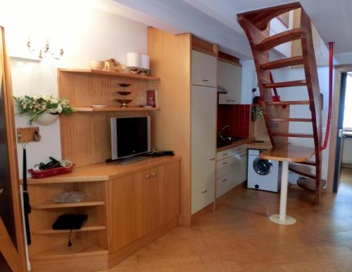 a room with a desk with a television and a ladder at Alberti - Condominio Villa Golf in Madonna di Campiglio