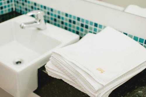 uma casa de banho com 2 toalhas brancas num lavatório em Hotel Aladdin em Curitiba