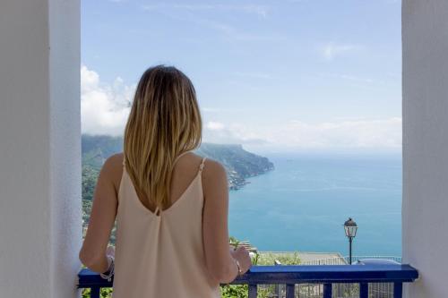 a woman looking out a window at the ocean at Angiem Holiday House Ravello in Ravello
