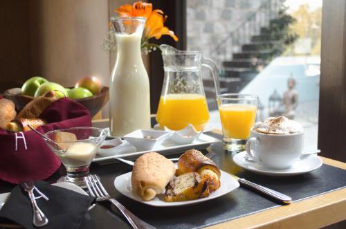 a table topped with plates of breakfast foods and orange juice at Aubrey Hotel Boutique in Santiago