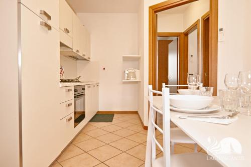 cocina blanca con mesa blanca y sillas en Appartamento Arianna, en Manerba del Garda