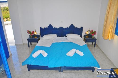 a blue bed with two pairs of slippers on it at Theophili in Zefiría