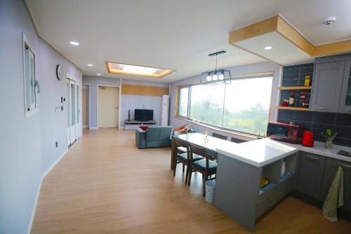 a kitchen and living room with a large window at Seong Ge Dol Pension in Seogwipo