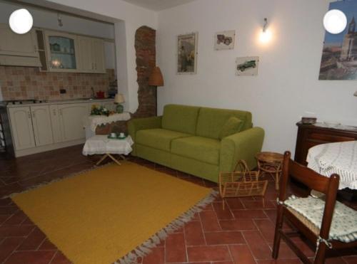 a living room with a green couch and a kitchen at Casale nel Borgo in Castiglione della Pescaia