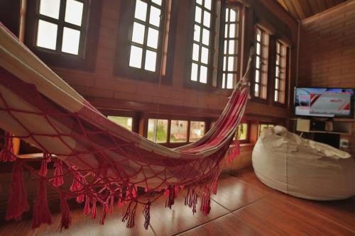 a hammock is hanging in a room with windows at EccO Capricornio in Caraguatatuba