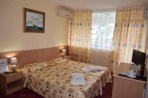 a hotel room with a bed and a window at Ahilea Hotel - Free Pool Access in Balchik