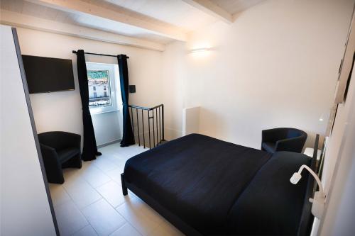 a bedroom with a black bed and two chairs at The House On The River in Bosa