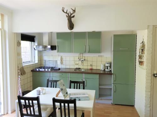 una cocina con armarios verdes y una mesa con sillas en Bungalow Hartje Veluwe, en Otterlo