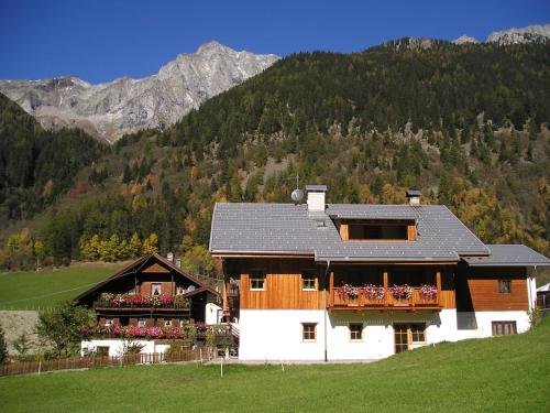 a house on a hill with mountains in the background at Müllerhof in Anterselva di Mezzo