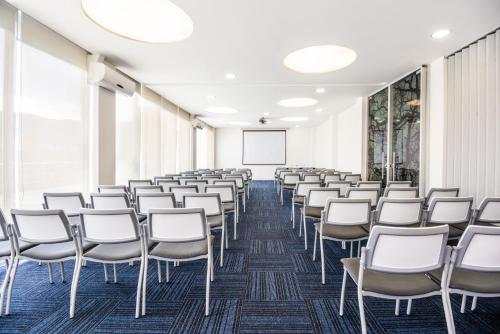 an empty room with white chairs and a whiteboard at SHG Bogotá 100 Design Hotel in Bogotá