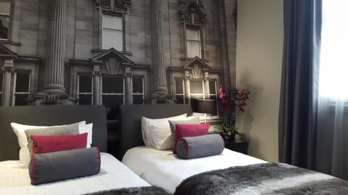 two beds with pillows in front of a building at Grey Street Hotel in Newcastle upon Tyne
