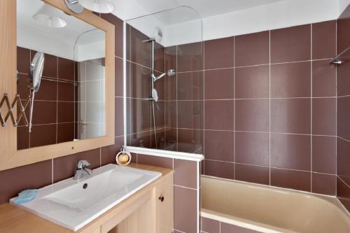 ein Badezimmer mit einem Waschbecken, einer Badewanne und einem Spiegel in der Unterkunft Residence Les Bergers - maeva Home in L'Alpe-d'Huez