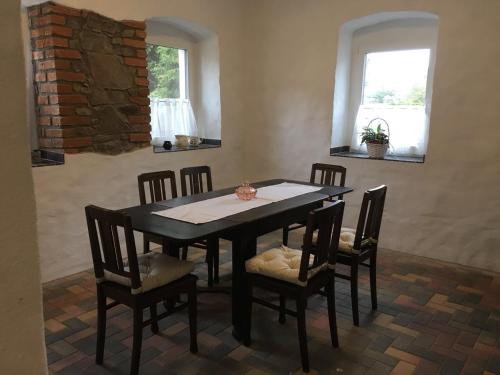 a dining room with a table and chairs and two windows at Gut Fischer in Pomssen