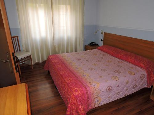 a bedroom with a bed with a pink bedspread at Hotel Capri in Lesa