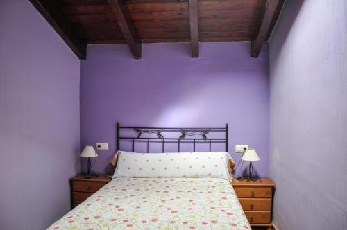 1 dormitorio con 1 cama con pared morada en Las Casitas de los Mata en Landete