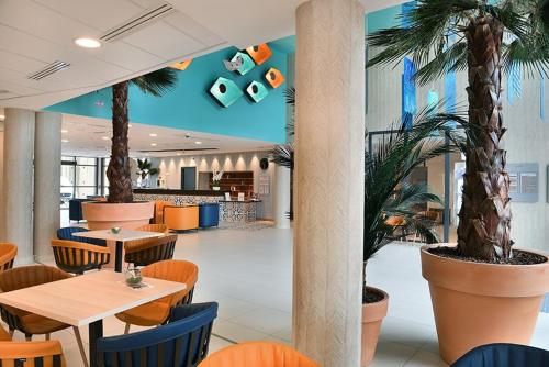 un restaurant avec des tables, des chaises et des palmiers dans l'établissement Domitys Le Jardin Des Palmiers, à Ajaccio