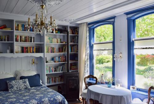 een slaapkamer met een bed, een tafel en boekenplanken bij Het Twiscker Huys in Twisk