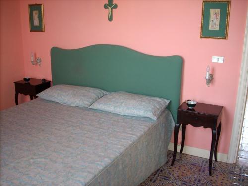 ミラッツォにあるDependance di Villa Elizabeth 4 posti lettoのベッドルーム1室(緑のヘッドボードとピンクの壁のベッド1台付)