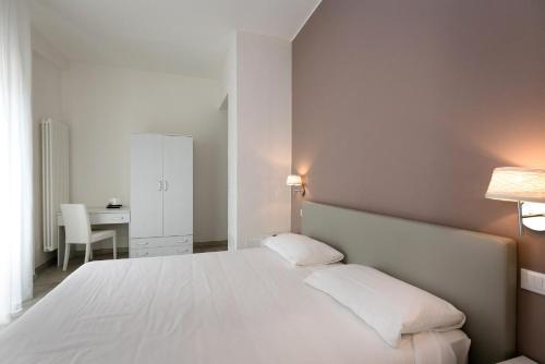 a bedroom with a large white bed and a desk at Hotel Saviola in Sirmione