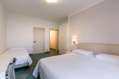 two beds in a room with two white beds at Hotel Saviola in Sirmione
