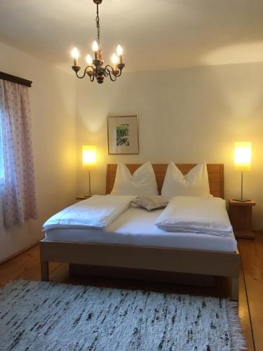 a bedroom with a bed with white sheets and a chandelier at Bergarbeiterhäuser in Altaussee