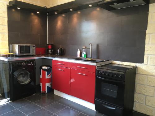 - une cuisine avec des placards rouges et un lave-linge dans l'établissement Appartement La Perle Noire, à Agde