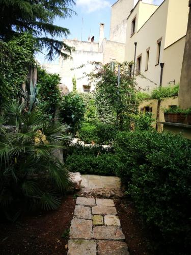 un jardin avec un chemin en pierre en face d'un bâtiment dans l'établissement B&B Corte San Giuseppe, à Casarano