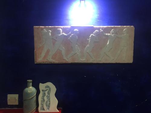 a painting hanging on a wall with vases and a light at Hotel George in Kalamata