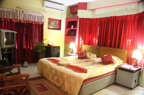 a bedroom with a large bed with red curtains at Babylon Hotel & Serviced Apartment in Dhaka