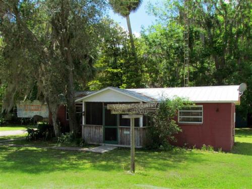 a small red house with a sign in the grass at The Yearling Cabins in Cross Creek