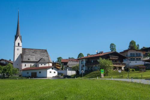 a village with a church and a green field at Pension Anneliese in Schwendt
