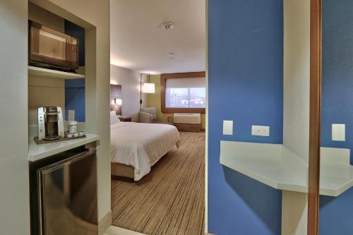 a hotel room with a bed and a room with a kitchen at Holiday Inn Express & Suites Portales by IHG in Portales