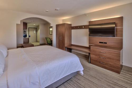 a hotel room with a bed and a flat screen tv at Holiday Inn Express & Suites Portales by IHG in Portales