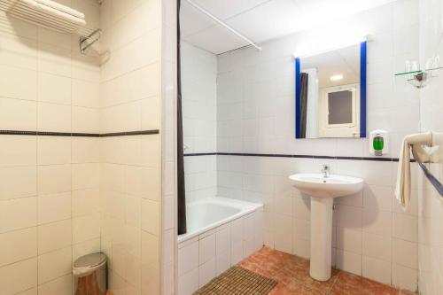 a white bathroom with a sink and a bath tub at Hostal Jentoft in Seville